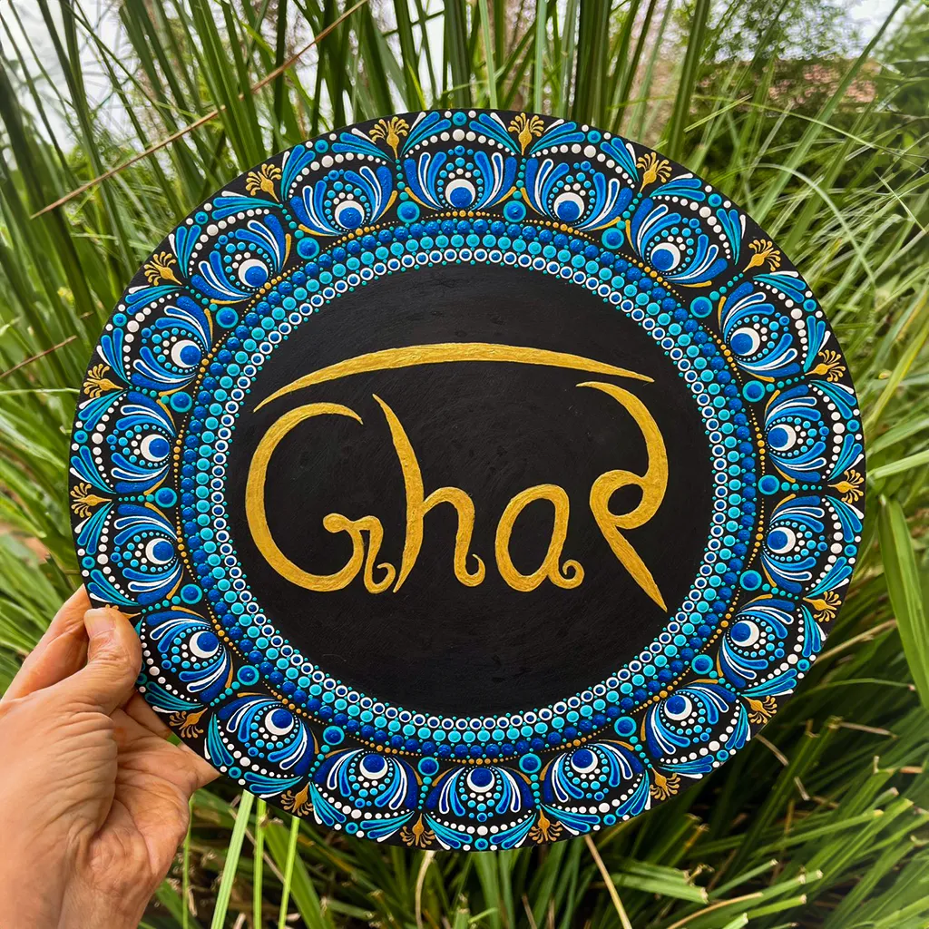 Dot Mandala Ghar Plate showcases the ancient art of dot painting, a technique that requires immense precision and creativity. Each dot is meticulously painted by hand to create stunning mandala patterns that radiate harmony and positivity. The vibrant blue, gold, and white tones are perfectly balanced, giving the plate an elegant yet lively appearance. At the center, the word “Ghar” (meaning “Home” in Hindi) is written in graceful gold lettering, making it a heartwarming symbol of love and belonging.