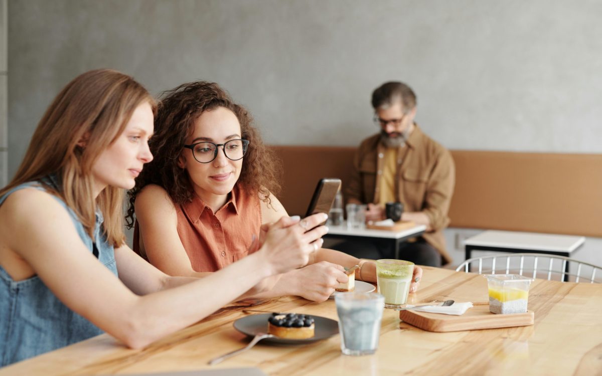  Friends hanging out at a local café using Upswap to save, shop, and stay lit