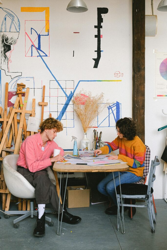 Teenager sitting at a table, surrounded by colorful craft supplies and working on a DIY project.