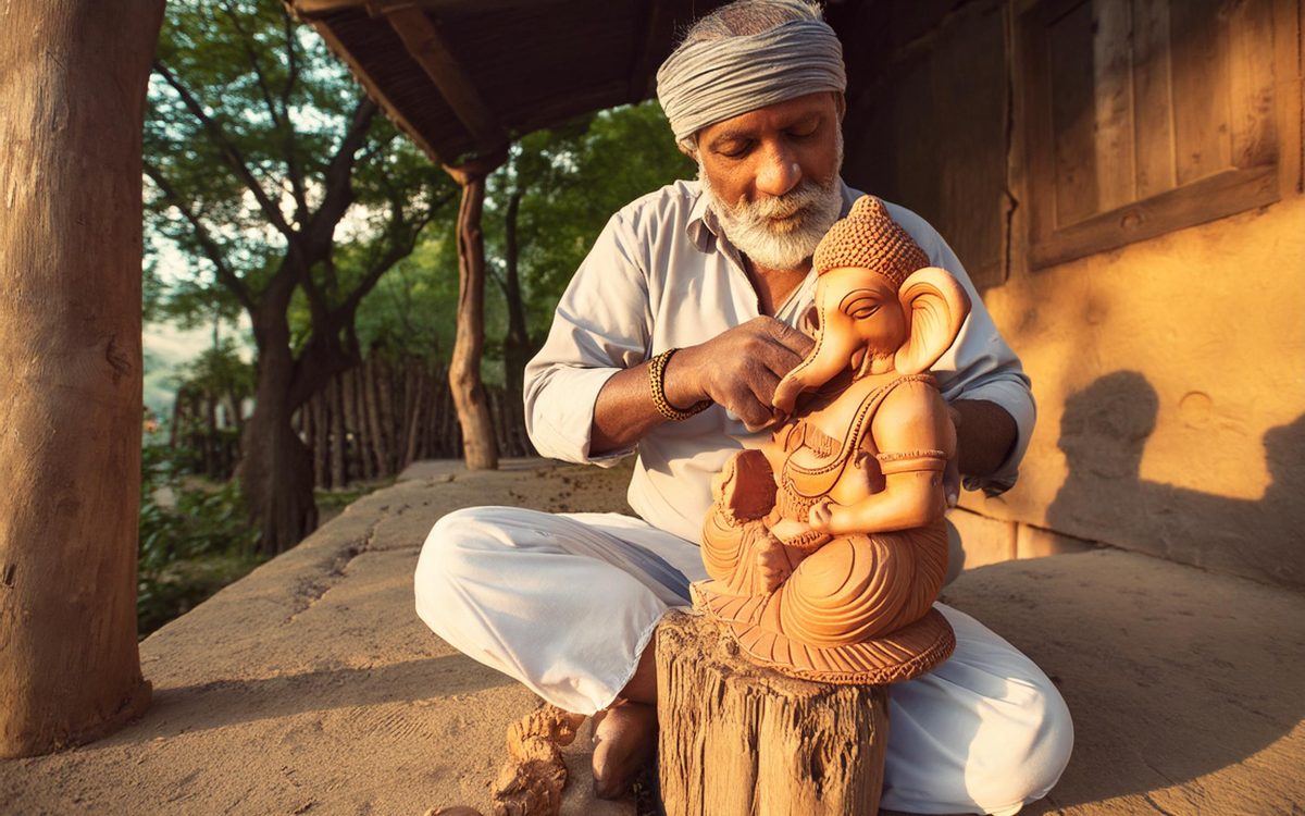 an Indian old artisan carving a wooden idol of lord Ganesha