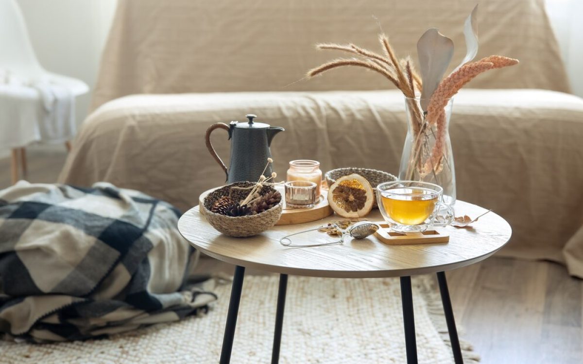 A colorful handwoven rug with geometric patterns sits beneath a wooden coffee table adorned with a brass vase and terracotta teacups.